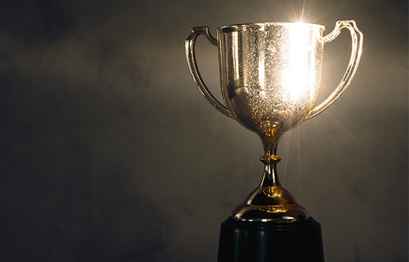 Gold trophy lit by a bright spotlight.