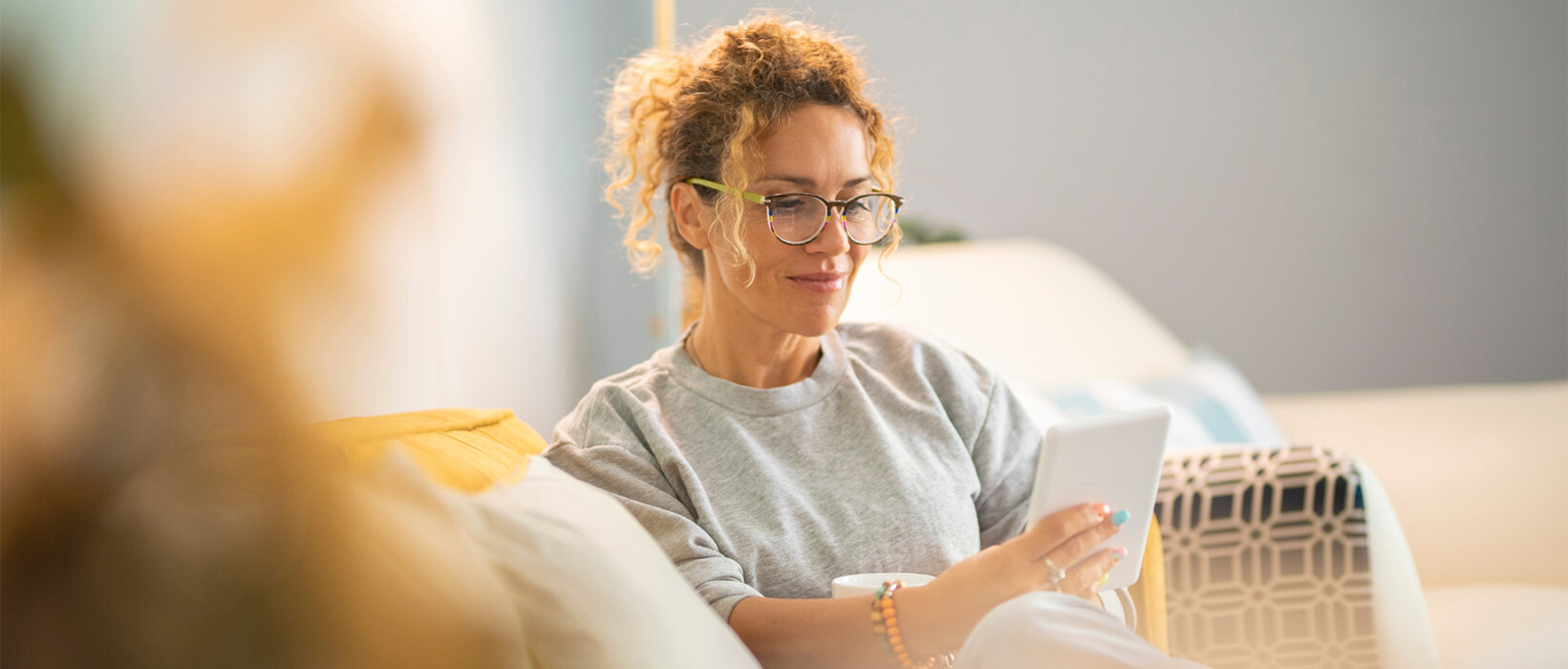 Person relaxing at home while reading on a tablet.