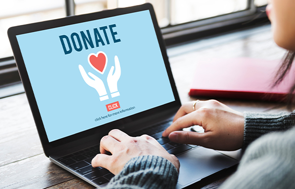 Person using a laptop with a donation page on screen.