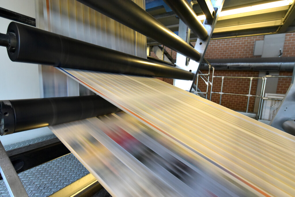 Newspapers moving through a high-speed printing press.