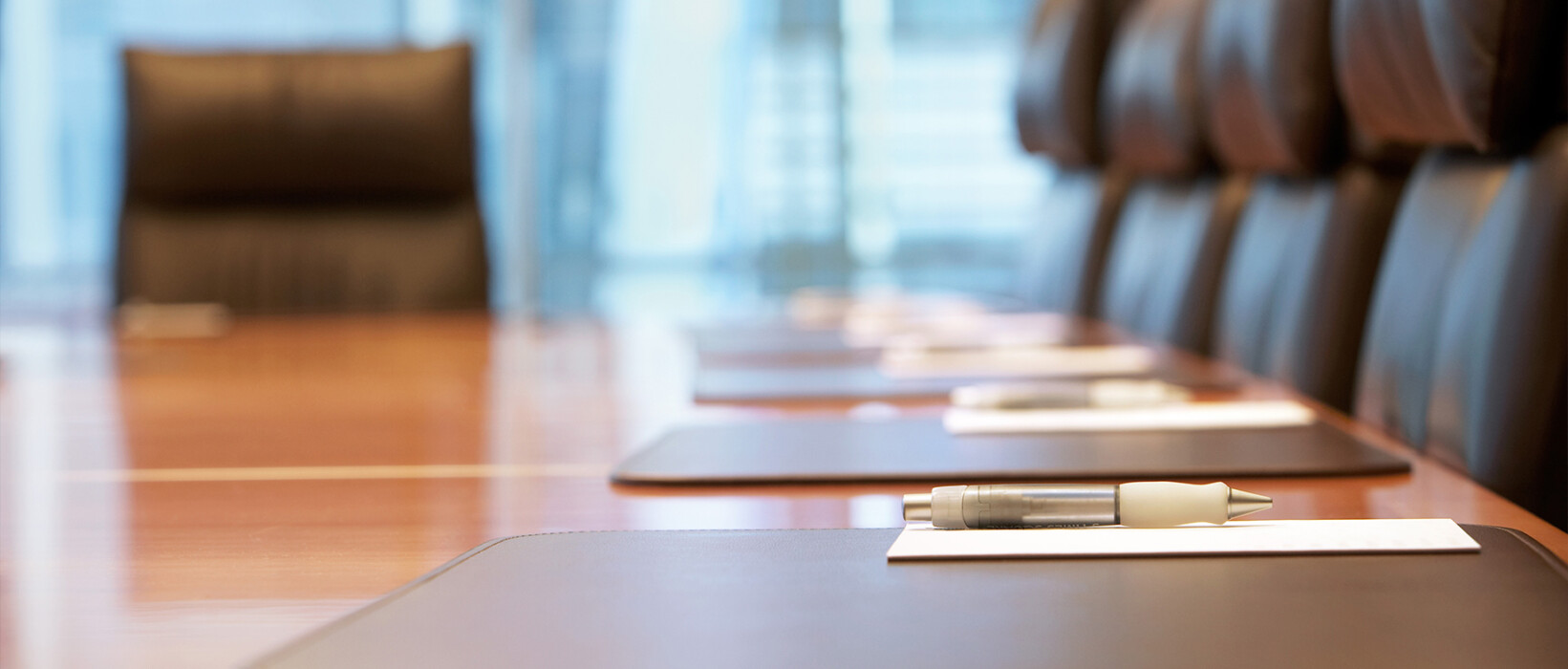 Boardroom table with meeting materials and a pen.