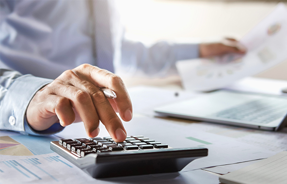 Person using a calculator while reviewing advertising documents.